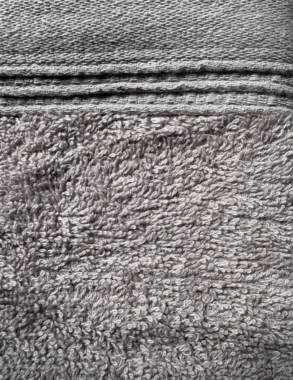 Close-up of a gray textured fabric with a woven top section and a plush terry-like lower section.