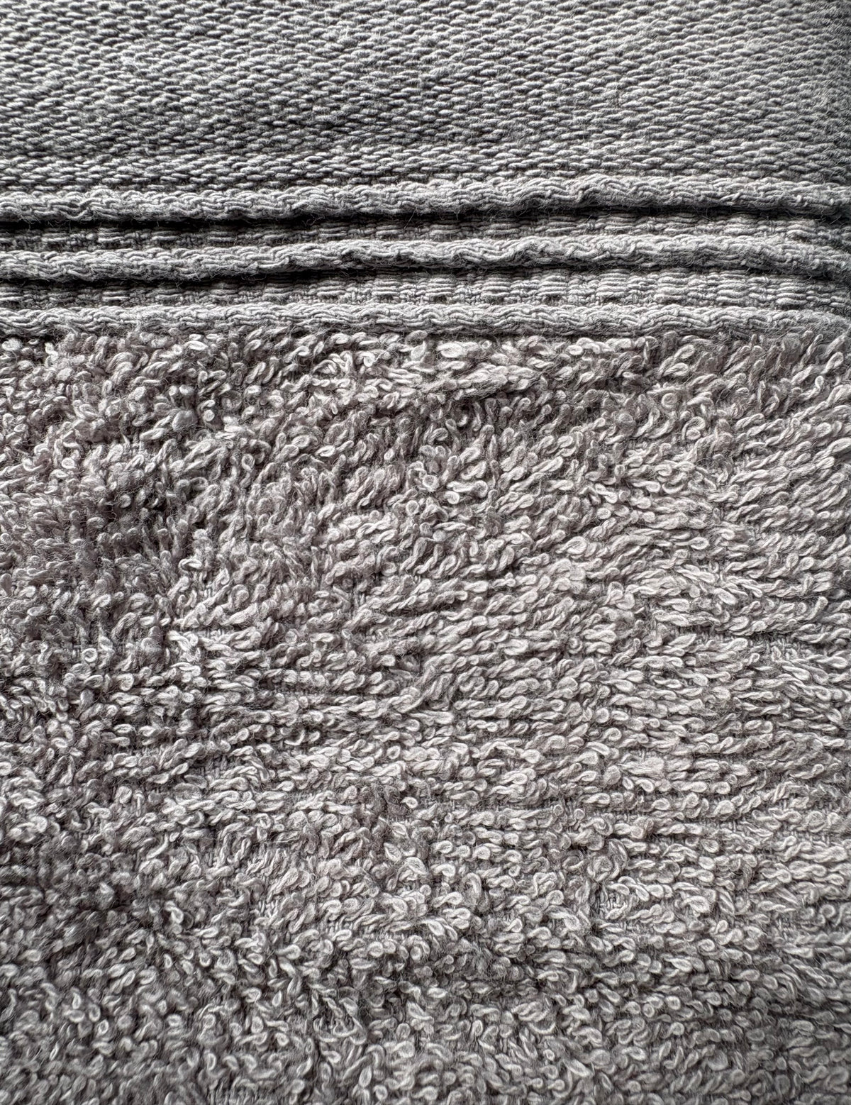 Close-up of a gray textured fabric with a woven top section and a plush terry-like lower section.